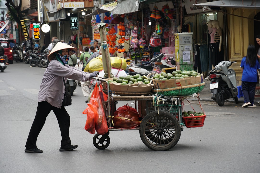 A woman pushing a cart full of produce down a street