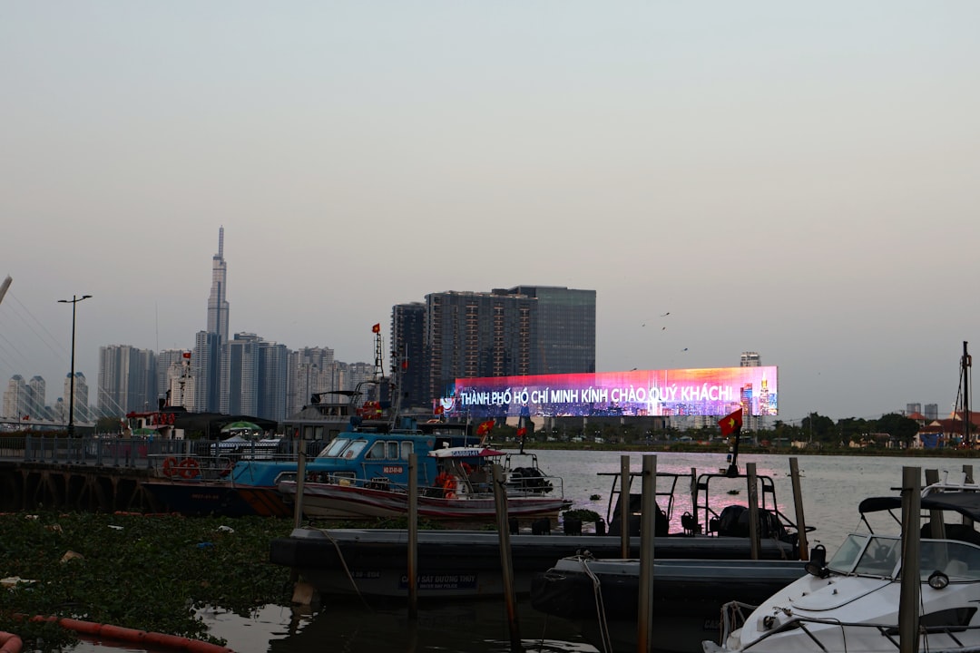 Boats docked on a river with a cityscape background.