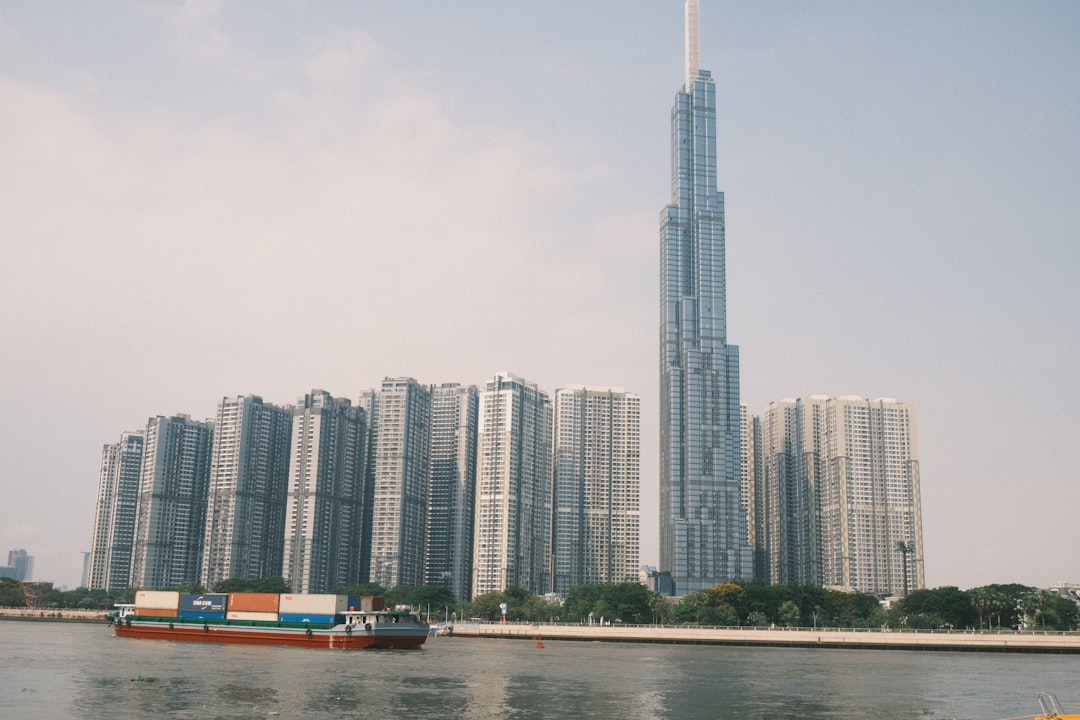 A barge carrying containers sails past tall buildings.