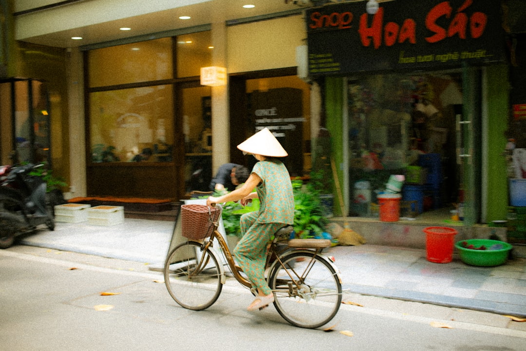 Woman in conical hat rides bicycle down street.