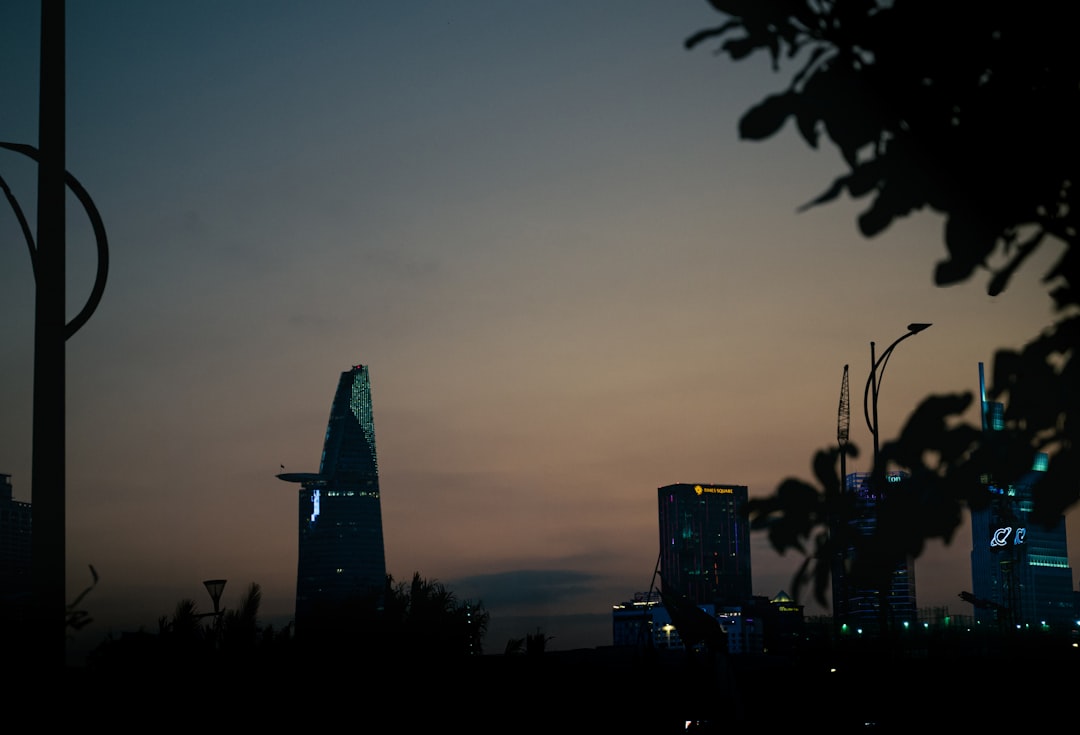 City skyline at twilight with tall modern buildings and trees.