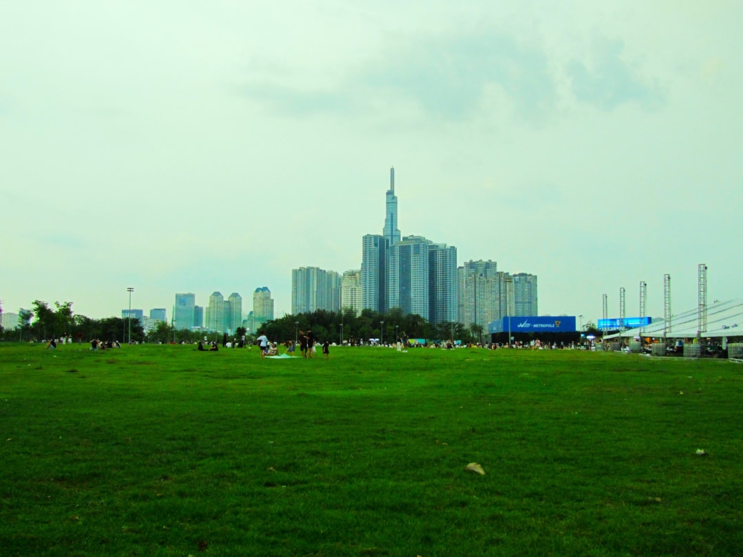 Modern cityscape behind a vast green field.