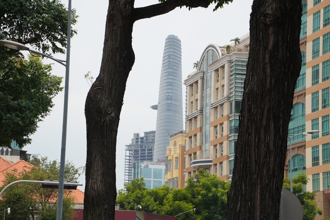 A tall skyscraper rises above city buildings and trees.