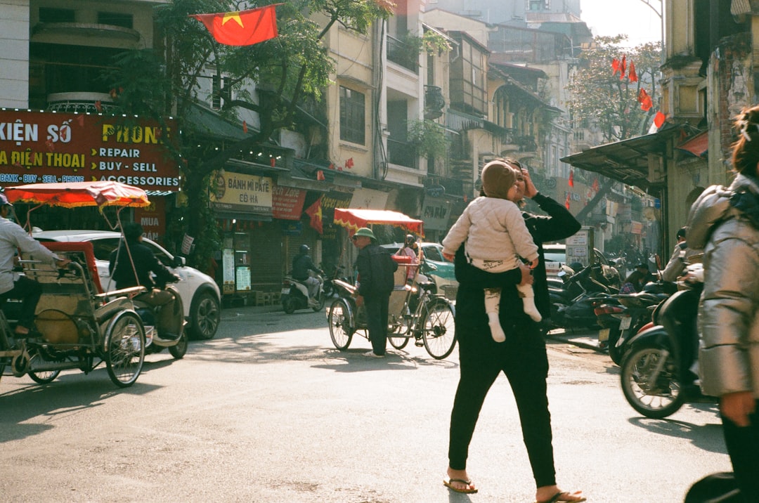 Woman carries child on shoulders in busy street