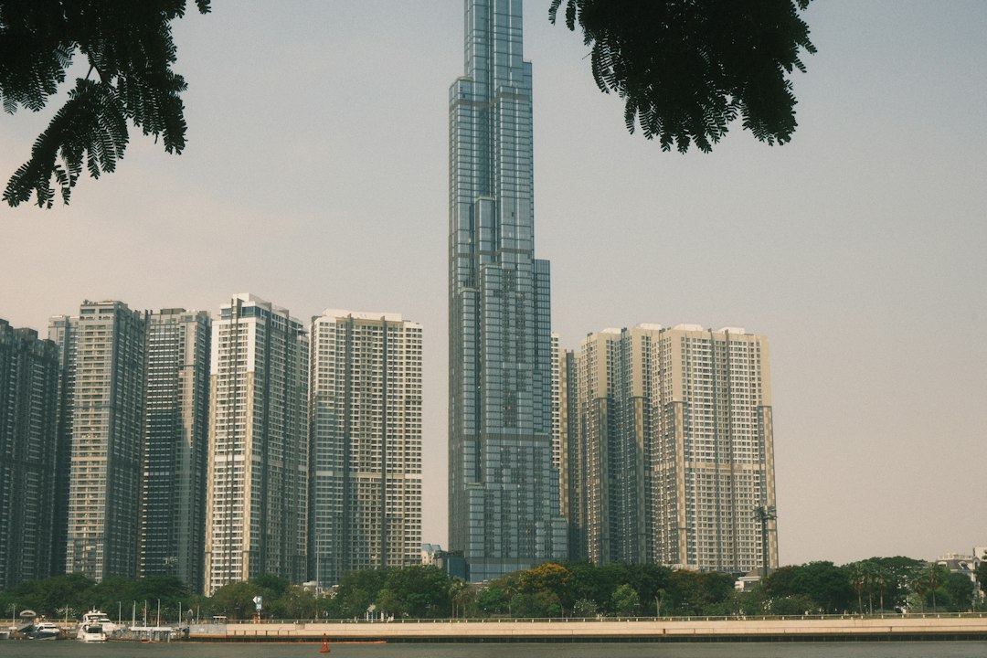 Modern skyscrapers rise above a tree-lined waterfront