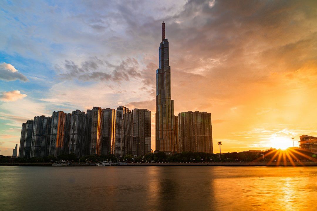 Landmark skyscraper rising above a city skyline at golden hour by a river